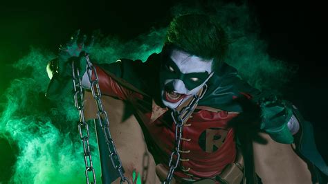 a man dressed up as the joker with chains around his neck and hands in ...