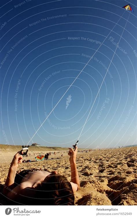 Kite flying on the beach - boy lying in the sand flying a kite - a ...