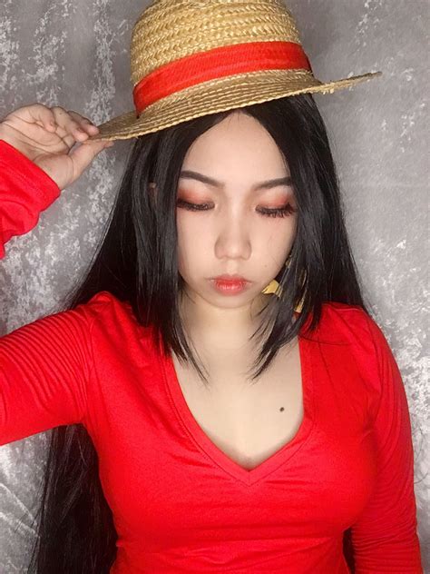 a woman with long black hair wearing a red shirt and a straw hat on her ...