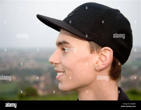 Young man wearing baseball cap smiling portrait side view close up ...