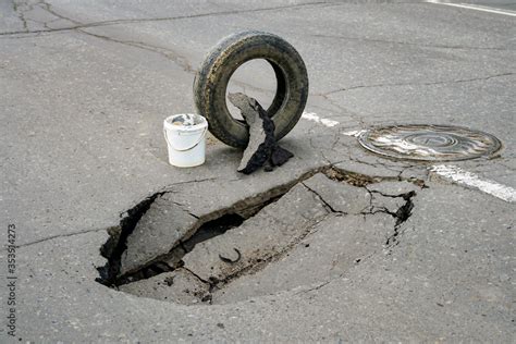 huge pit hole on the road, failure in the asphalt, marked with a tire ...