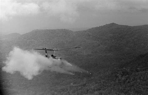 An armed helicopter fires a salvo of rockets toward a Viet Cong jungle ...