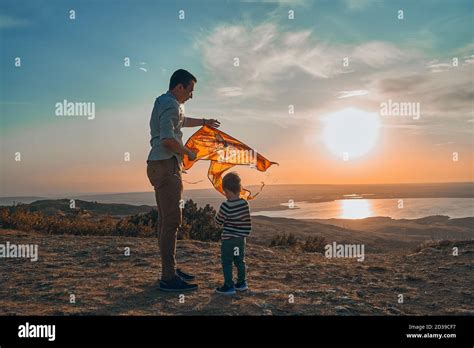 A little boy and his father play flying kite in nature at sunset Stock ...