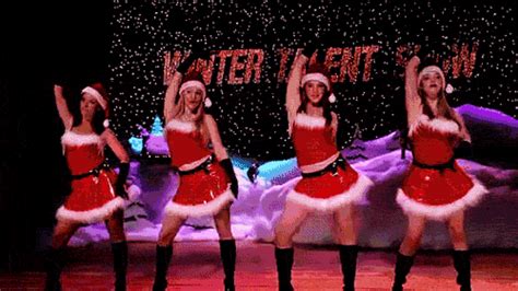 four women dressed in santa claus outfits on stage with their arms up ...