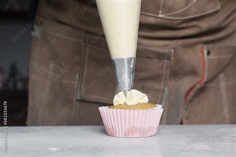 Piping buttercream on a vanilla cupcake, decorating cupcakes, hand ...