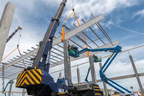 Construction worker working at boom lift installation steel roof beam ...