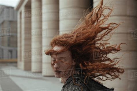 Wind blowing hair of Caucasian woman near pillars - Stock Photo - Dissolve