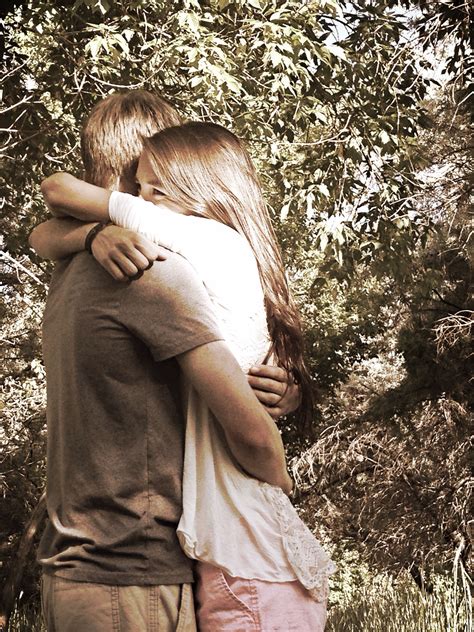 Girl smiles and looks off into the distance. While the guy is hugging ...