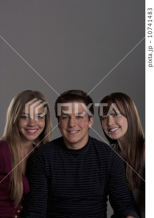 Portrait of teenage boy (16-17) and girl (16-17) with young friend, studio shot 10741483