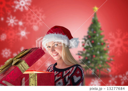 Composite image of festive blonde opening a gift 13277684