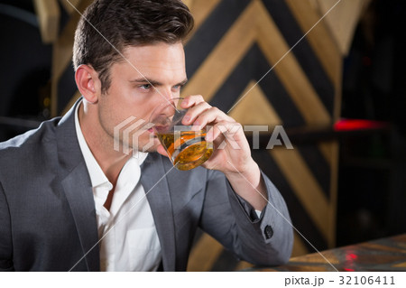 Depressed man having glass of whisky at counter 32106411