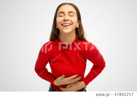 Positive and joyful girl keeps both hands on belly 47802257