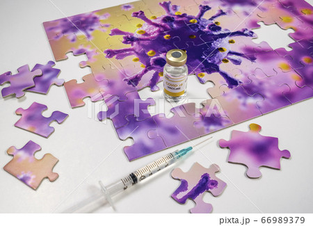 Studio shot of puzzle with Coronavirus model and vaccine vials and syringe 66989379