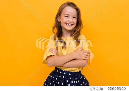 stylish charming young smiling girl in a light yellow blouse and skirt on a yellow background 62006390