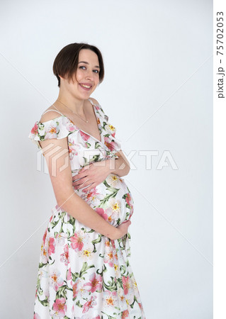 Studio portrait of cheerful young pregnant woman in summer dress on white gray background, happy pregnancy concept 75702053