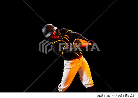 American baseball player, pitcher in sports uniform and equipment playing baseball isolated on black studio background in neon light. Rear view 79339923