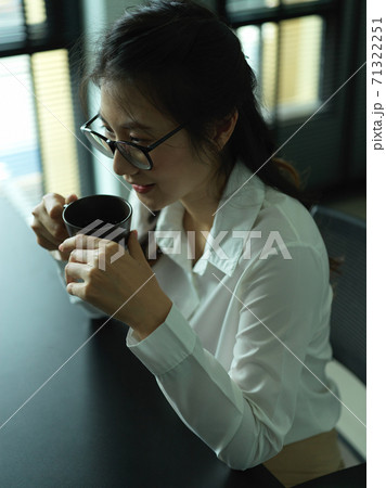 Female office worker relaxing with coffee in office room 71322251