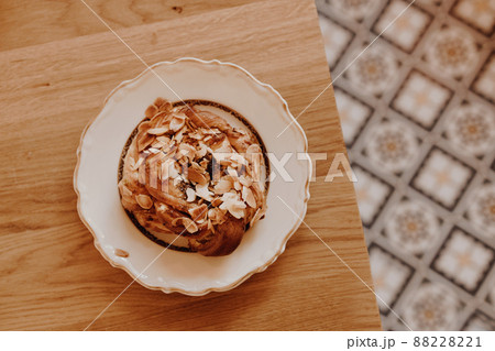 Breakfast time. Sweet cake with cream, almonds on a beautiful plate on a wooden table 88228221