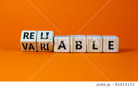 Variable or reliable symbol. Turned wooden cubes and changed the word variable to reliable. Beautiful orange background, copy space. Business and variable or reliable concept. 83914133