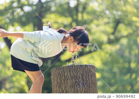 夏の公園で水遊びしている可愛い小学生の女の子の姿 90699492