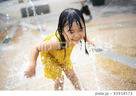 駅前広場の噴水で水浴びして遊んでいる女の子 93918573