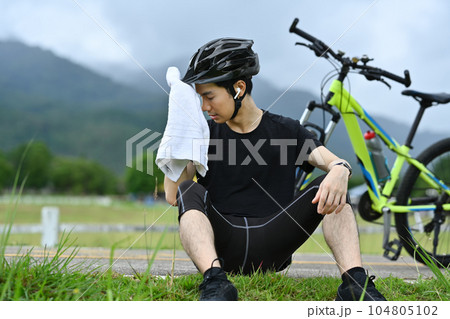 Handsome man in sport clothes taking a break from cycling bike in the morning. Outdoor sport activity and healthy lifestyle concept 104805102