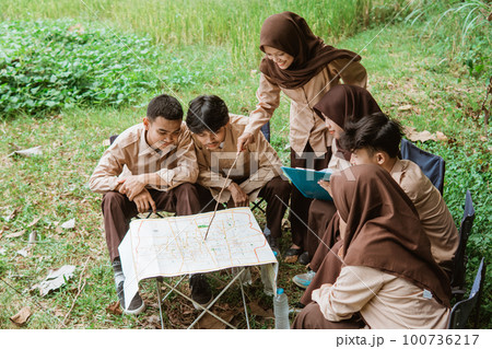 leader of the youth scout group gathered to discuss maps 100736217