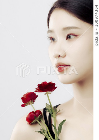 Beautiful girl holding some red persian buttercup flowers and looking aside 100974364