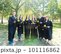 Group of young happy student graduates in gowns having fun in the park. Smiling students drinking champagne together. 101116862