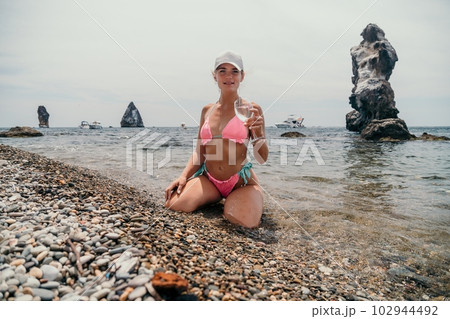 Woman travel sea. Traveler woman captures sea memory in pink bikini. Happy tourist poses on beach amidst volcanic mountains for adventurous journey. 102944492