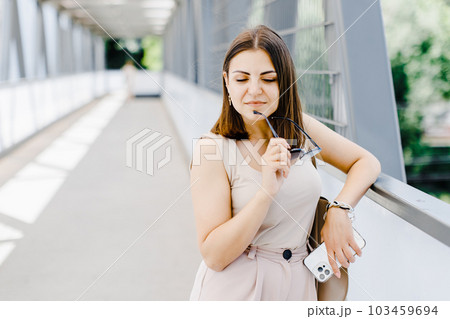 Happy young business woman holding mobile phone while walking on the street. 103459694