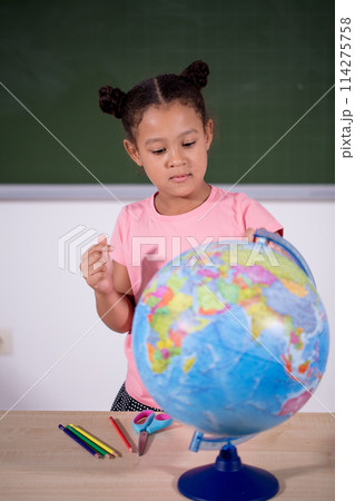 african schoolgirl looking globe with chalk background 114275758