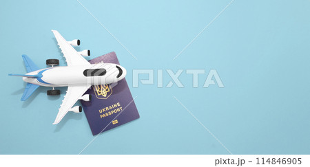 Layout of a white plane with a Ukrainian passport on a blue background. Summer vacation and plane travel, booking tickets 114846905