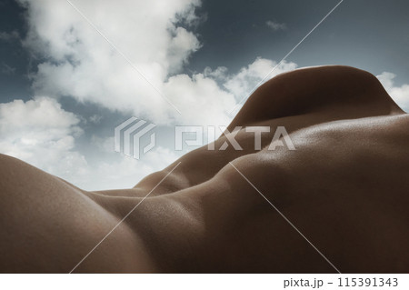 Human form and the sky blend into one continuous landscape. Male relief body, back blending with natural sky background. Sense of peace and harmony 115391343