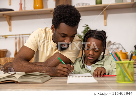 Smiling African American dad doing homework during homeschooling time 115465944