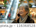 An elderly asian pensioner grandmother speaks on the phone in a shopping center. New communication technologies 116368528