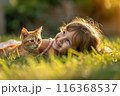 Happy little girl with ginger cat playing in green grass backyard. Having fun with your pet 116368537