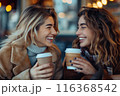 Two happy girls are sitting near cafe and drinking coffee. Communication with friends and lifestyle 116368542