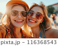 Two happy caucasian girls take a selfie outdoors on a sunny day. Smiling girlfriends take pictures on a mobile phone. Lifestyle. Close-up 116368543