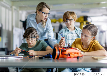 Children learning robotics in Elementary school. Young students building robot in after school robotics club. Field trip to real robotics laboratory. 116317172