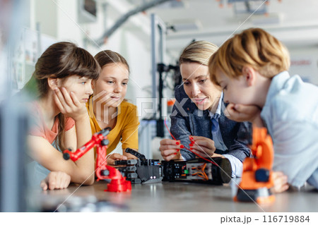 Children learning robotics in Elementary school. Young students building robot in after school robotics club. Field trip to real robotics laboratory. 116719884