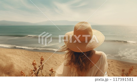 back view of woman in summer sun hat standing by sea or ocean water an looking at nature, follow me 117391581