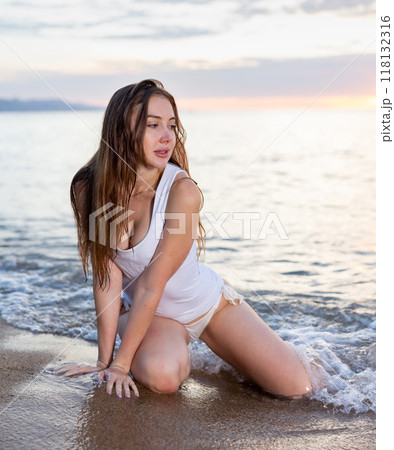 Attractive woman posing on sandy sea beach at sunset background 118132316