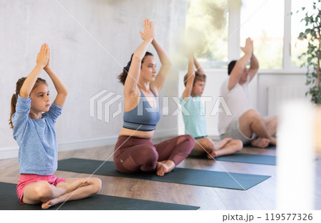 Mom with her family practices yoga in lotus position 119577326