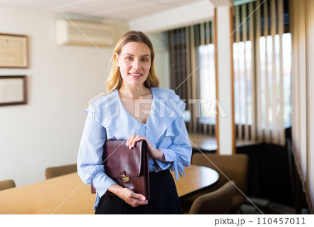 Positive businesswoman with briefcase for documents 110457011