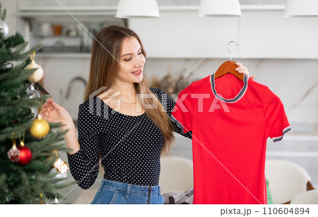 Portrait of attractive woman selecting dress for Christmas celebration 110604894