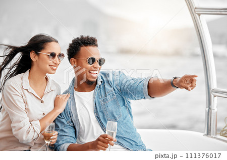 Couple love to travel on a luxury yacht at sea together on a romantic date in nature on a holiday vacation. Smile, happy and young boyfriend and woman enjoy champagne in the ocean on a boat cruise 111376017