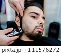 A man sitting in a barbers chair having his beard trimmed 111576272