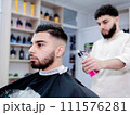 Black hair barber cutting facial hair on forehead, jaw, and neck 111576281