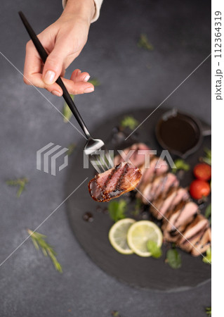 sliced grilled cooked piece of tuna fillet on black stone serving board 112364319